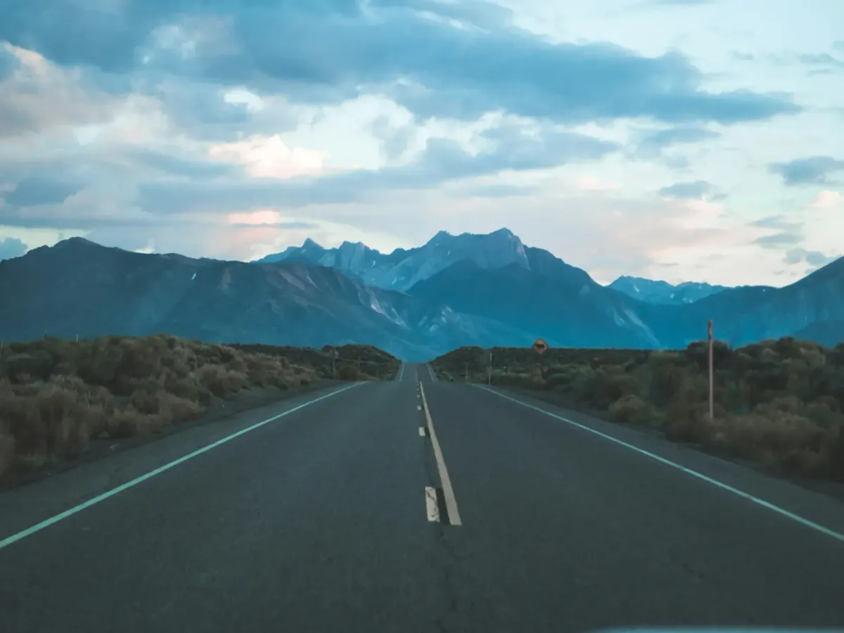 A road stretching forward into open sky with mountains in the background