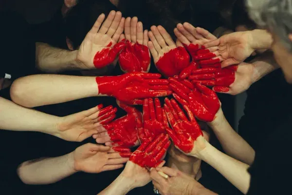 Hands painted in different colors forming a heart shape