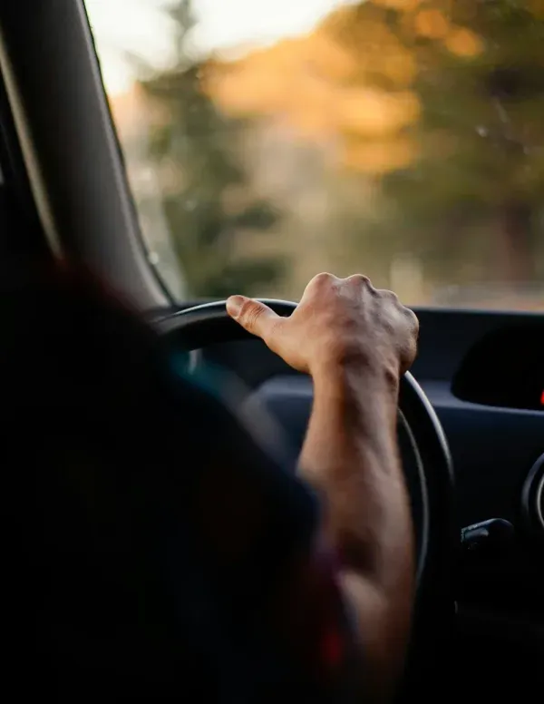 A hand holding a steering wheel while driving